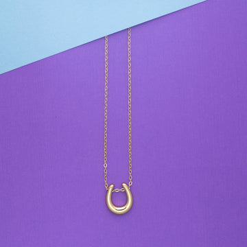 Gold necklace with a unique clasp on a purple and blue background