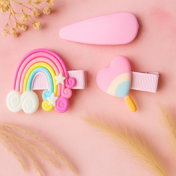 Two colorful hair clips on a pink background with dried flowers.