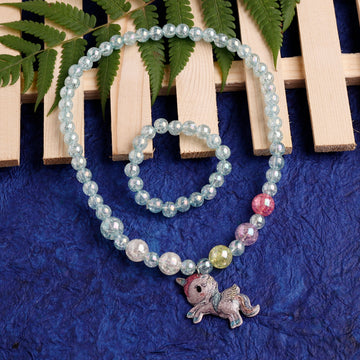 Beaded bracelet with a small figurine charm on a blue textured surface with green leaves in the background