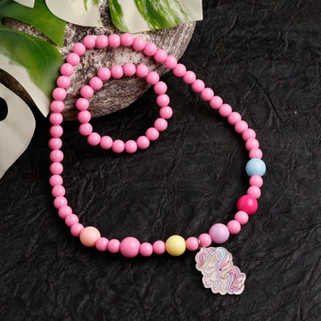 Pink beaded necklace with a unicorn charm on a dark textured surface
