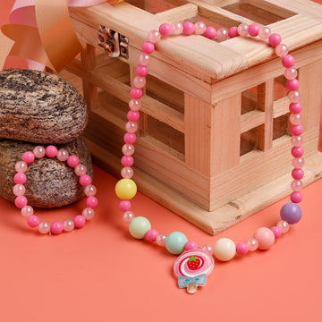 Colorful beaded necklace and bracelet on a pink surface with a wooden box in the background.