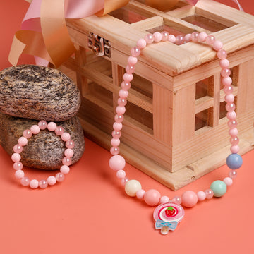 Pink beaded necklace with a decorative charm on a pink background
