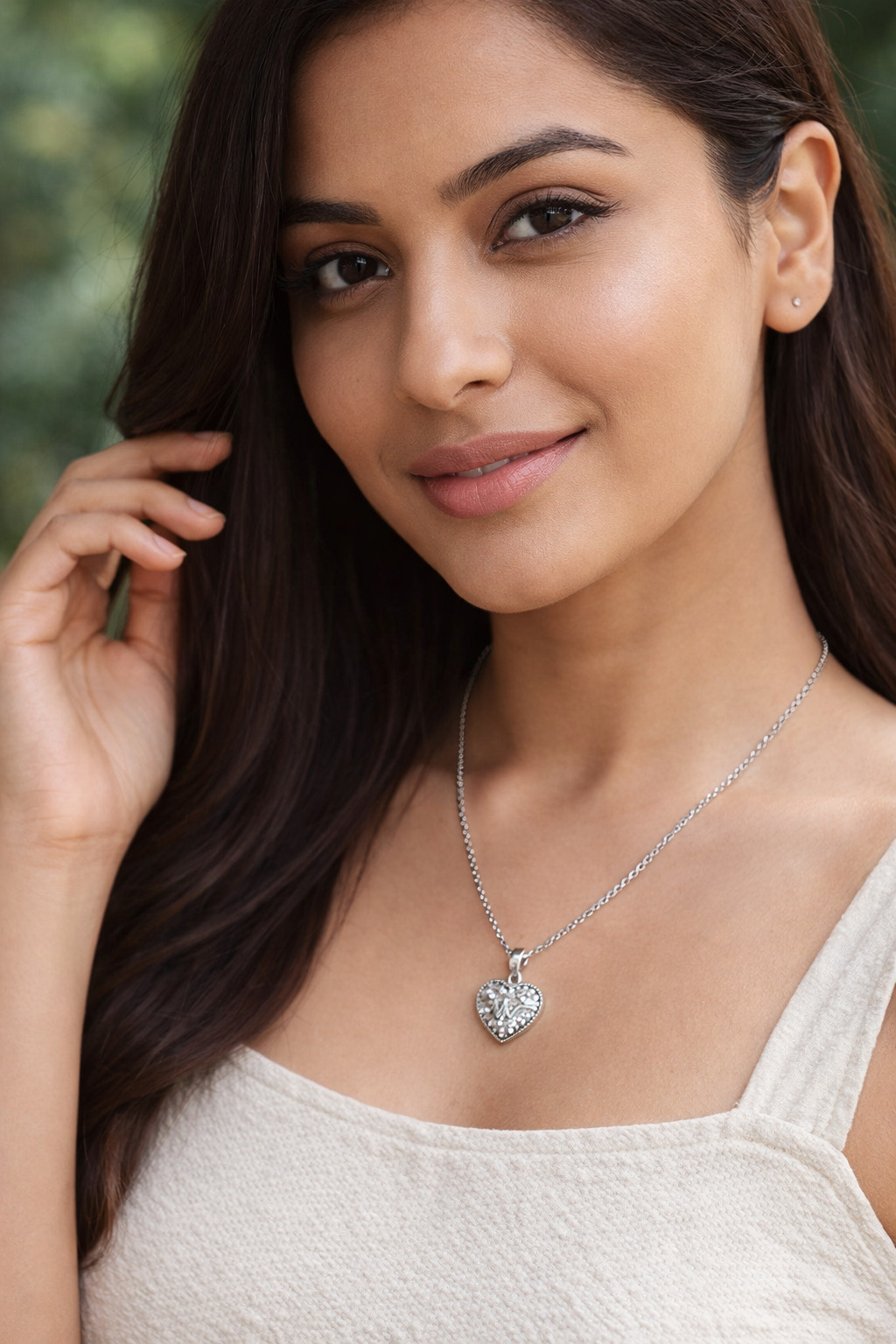 Woman wearing a silver necklace with a heart pendant outdoors