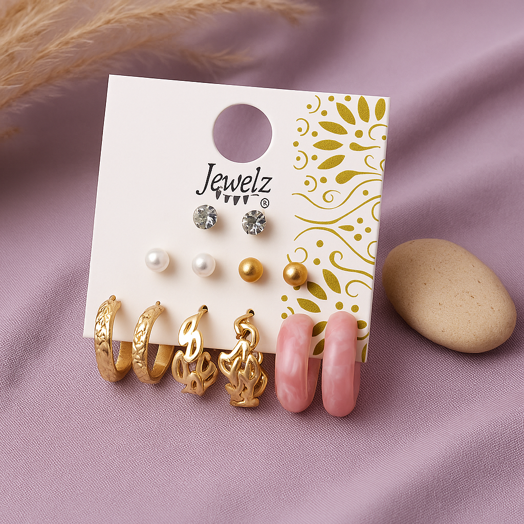 Set of earrings on a 'Jewelz' branded card with a stone and dried grass on a pink background