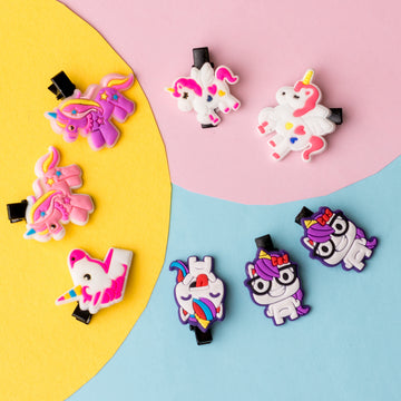 A collection of multicolored hair accessories including clips, bands, and scrunchies arranged on a two-tone background, pink at the top and blue at the bottom.
