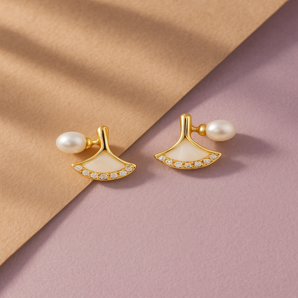 Gold earrings with pearls on a two-tone beige and pink background