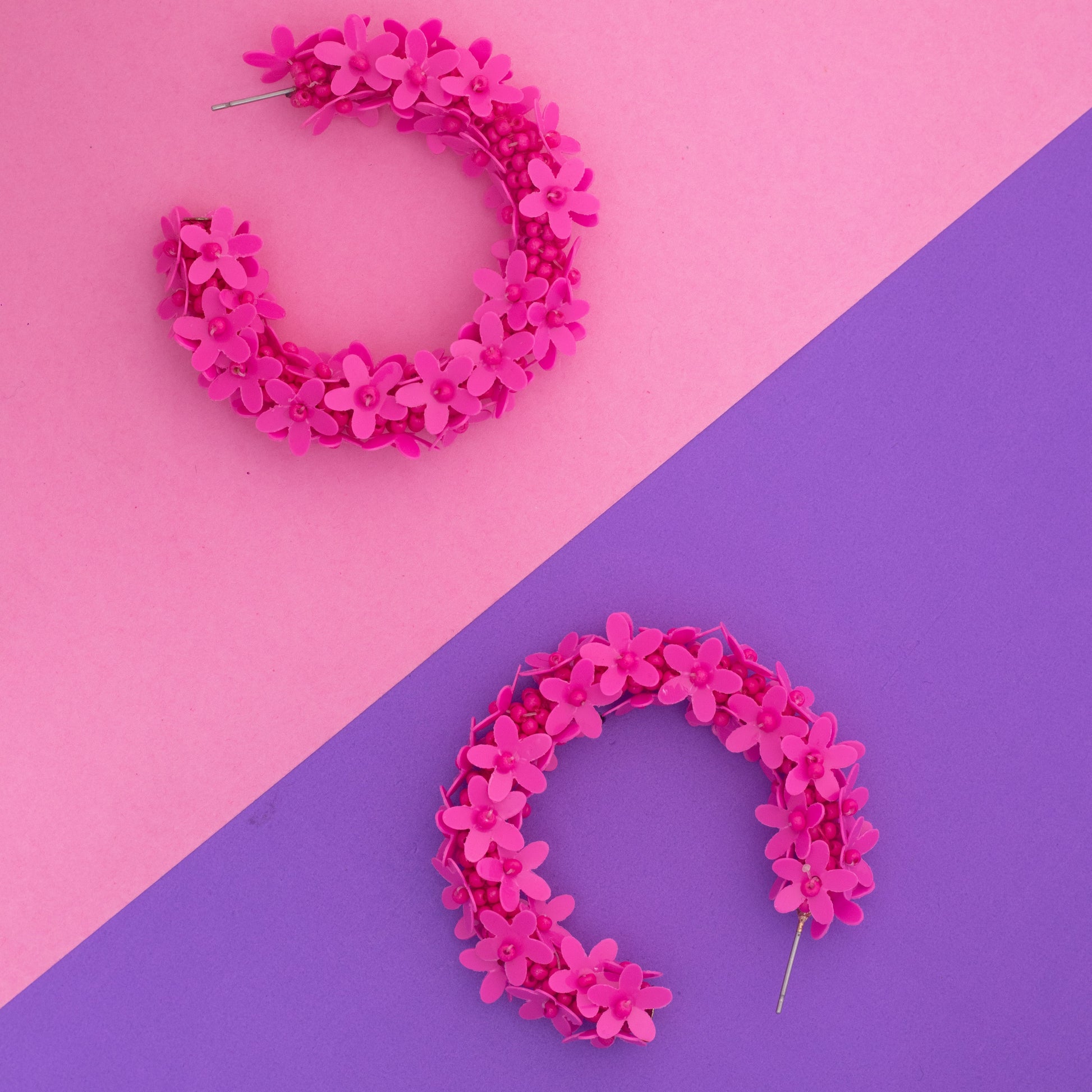 Pink floral hoop earrings on a pink and purple background