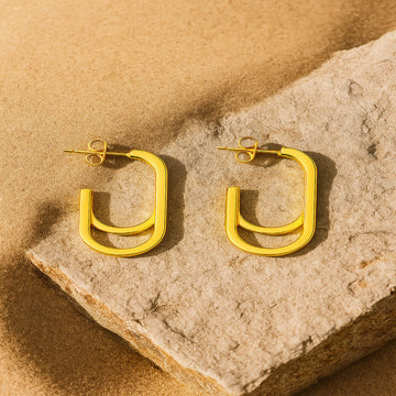 Gold hoop earrings on a stone surface