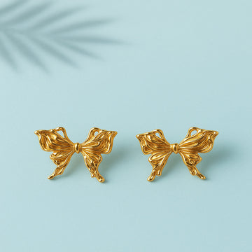 Gold bow-shaped earrings on a light blue background