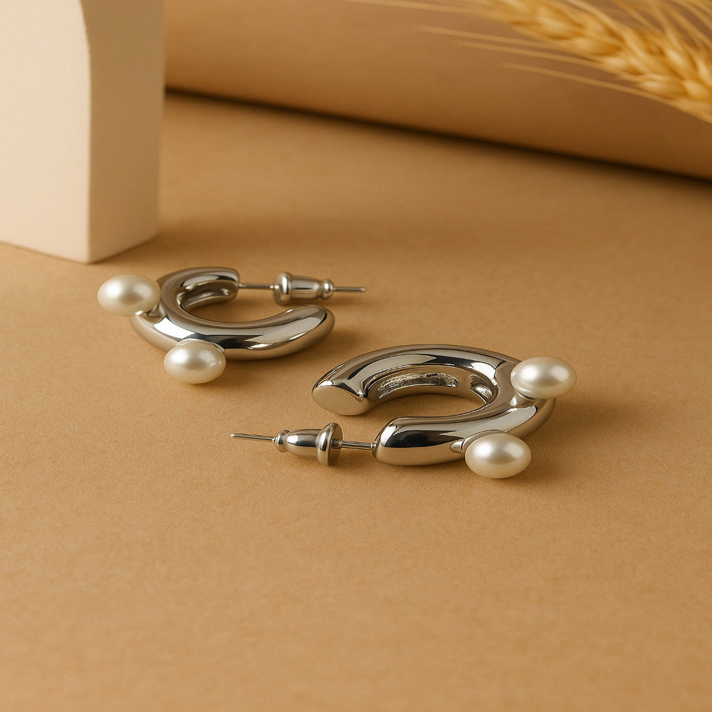 Silver hoop earrings with pearls on a brown surface
