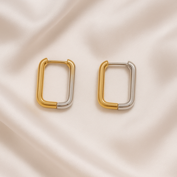 Pair of gold and silver hoop earrings on a beige satin background