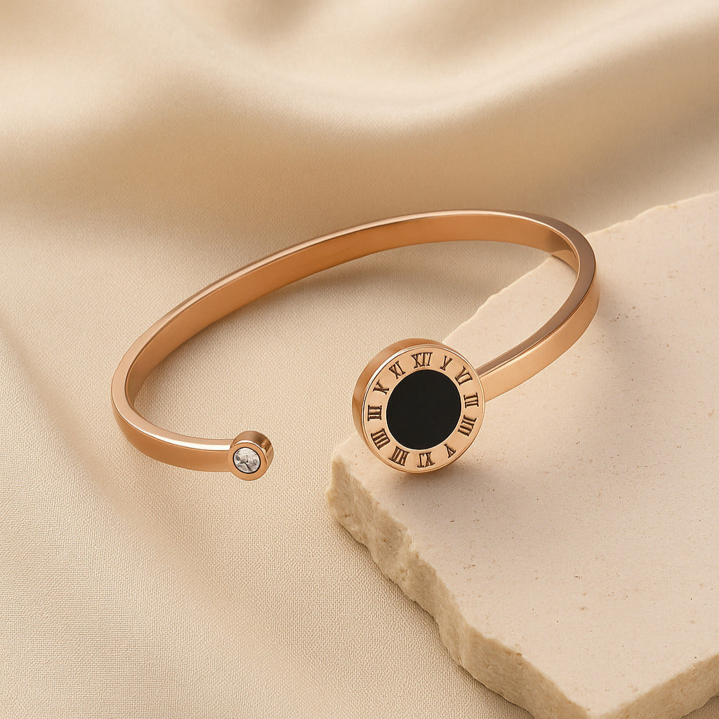 Rose gold bracelet with black center and Roman numeral design on beige fabric