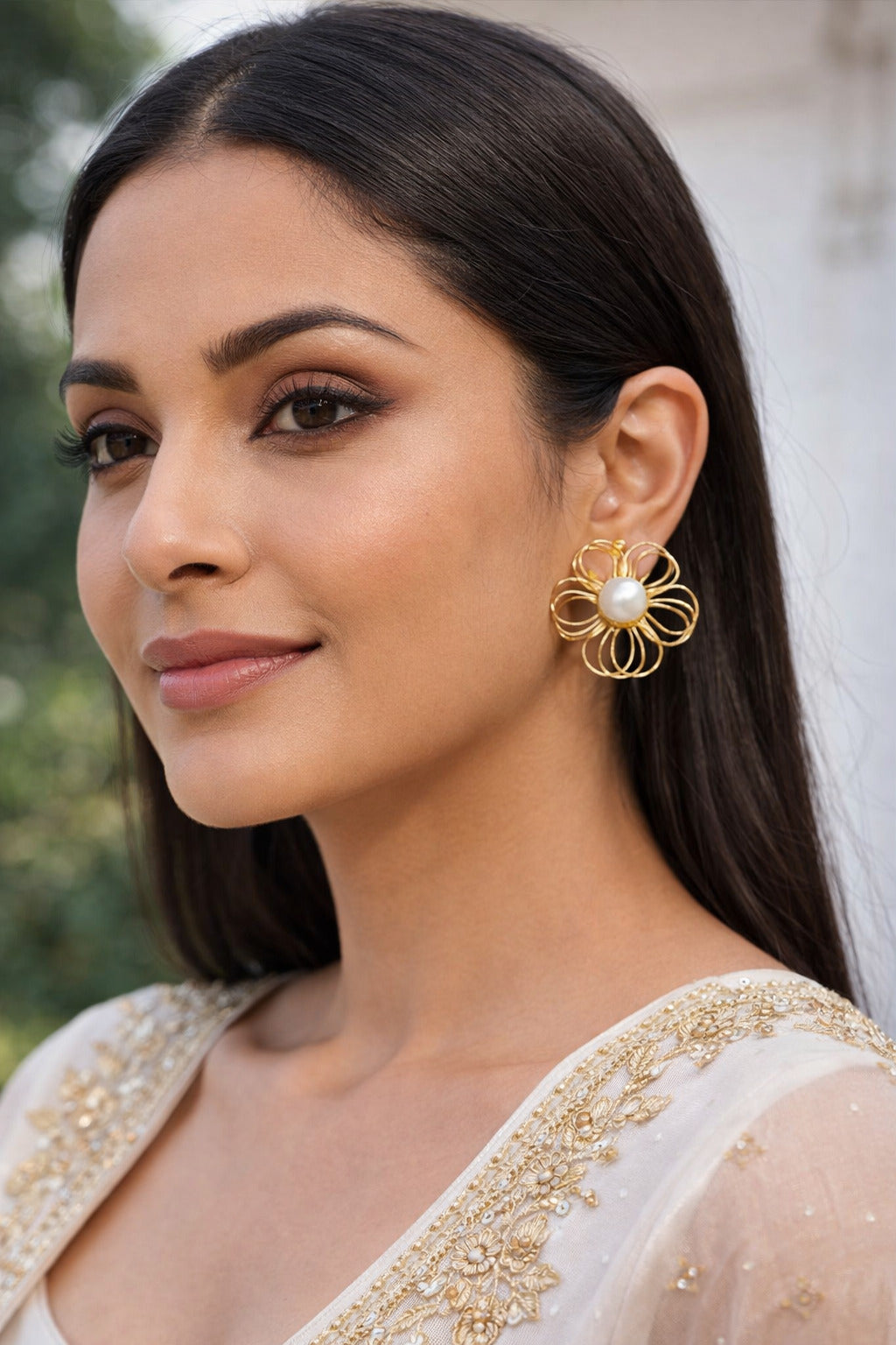 Woman wearing gold earrings with a blurred background