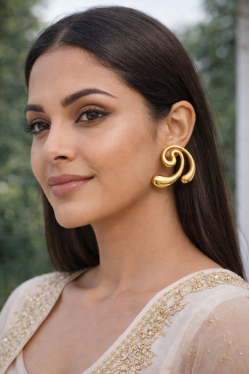 Woman wearing gold earrings with a blurred natural background