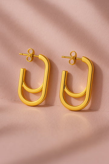 Gold hoop earrings on a pink fabric background