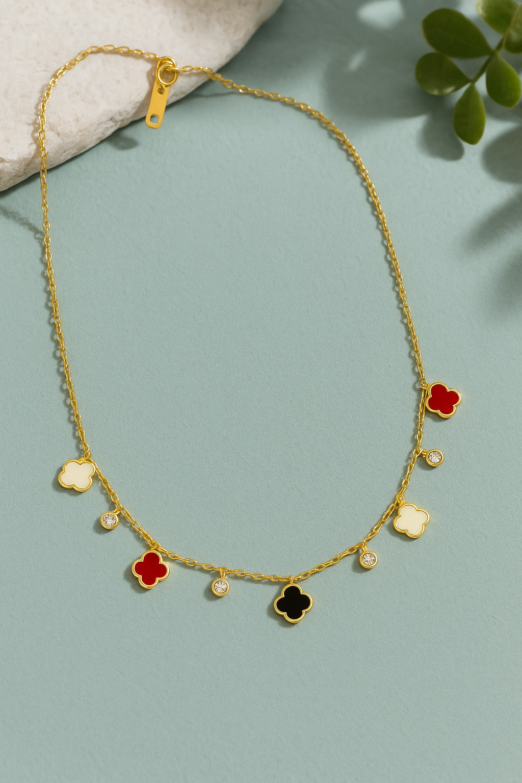 Gold necklace with colorful flower pendants on a light blue background