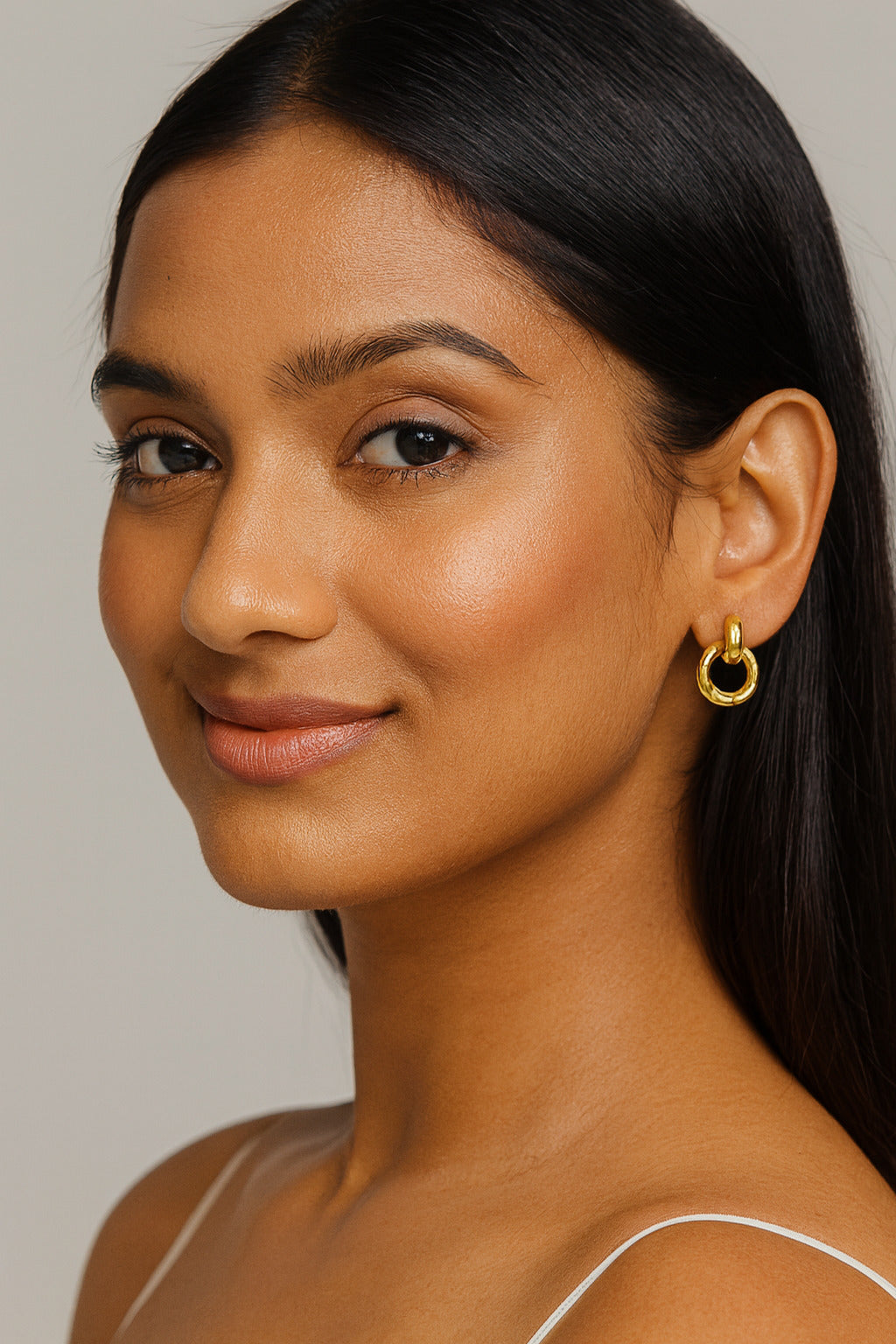 Woman wearing gold hoop earrings against a neutral background