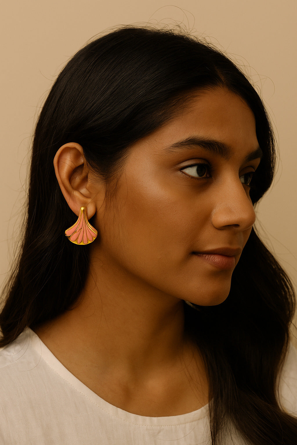 Woman wearing a pink shell earring against a beige background