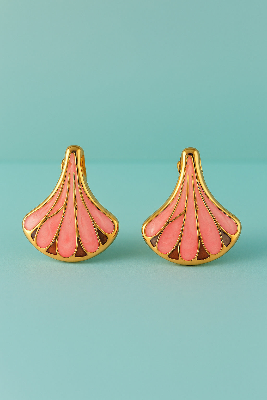 Pair of pink and gold earrings on a teal background