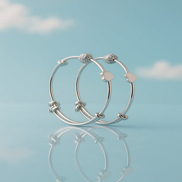 Silver hoop earrings with heart charms on a light blue background