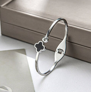 Silver bracelet with a clover-shaped charm on a light surface.