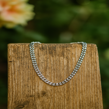 Silver chain on a wooden block with a blurred natural background