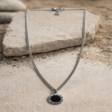 Necklace with a black pendant on a stone surface