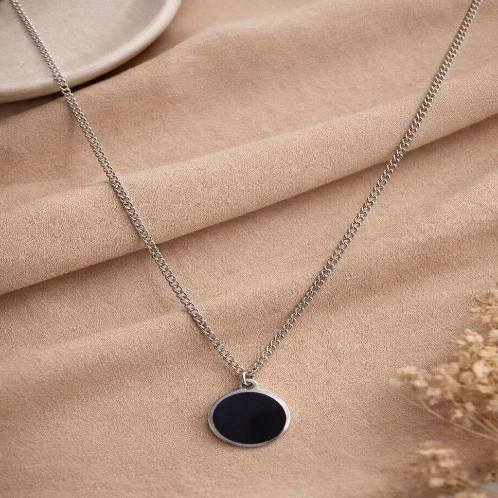 Necklace with a black pendant on a beige fabric background