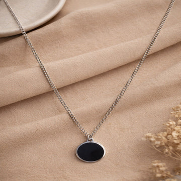 Necklace with a black pendant on a beige fabric background