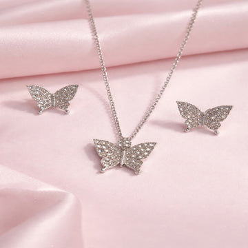 Butterfly-shaped jewelry set on a pink fabric background