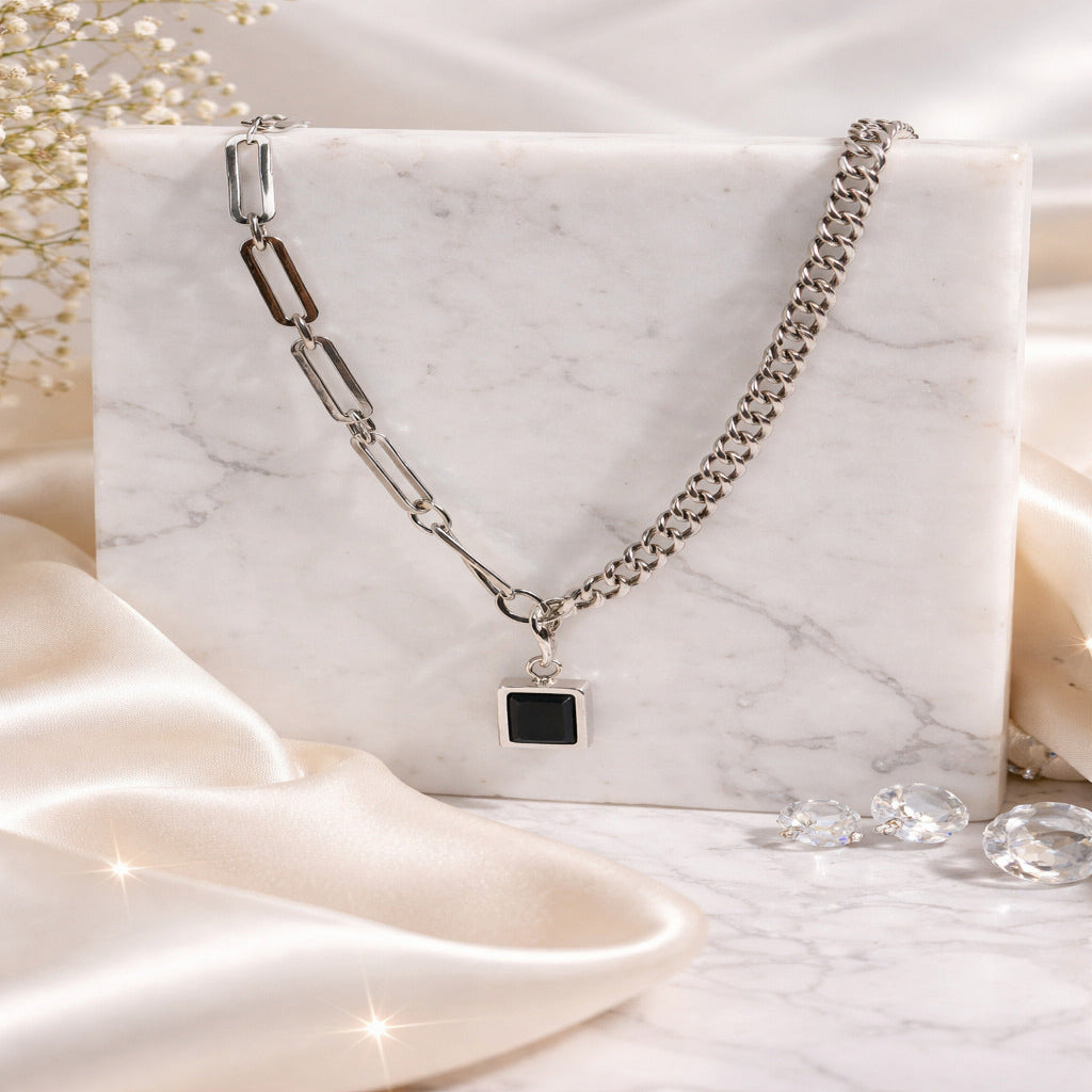 Silver chain necklace with a pendant on a marble surface with soft lighting