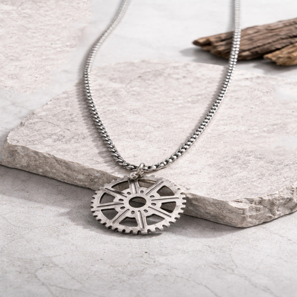 Silver gear-shaped pendant necklace on a stone surface