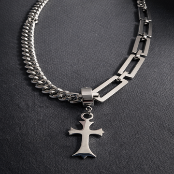 Silver chain necklace with a cross pendant on a dark background