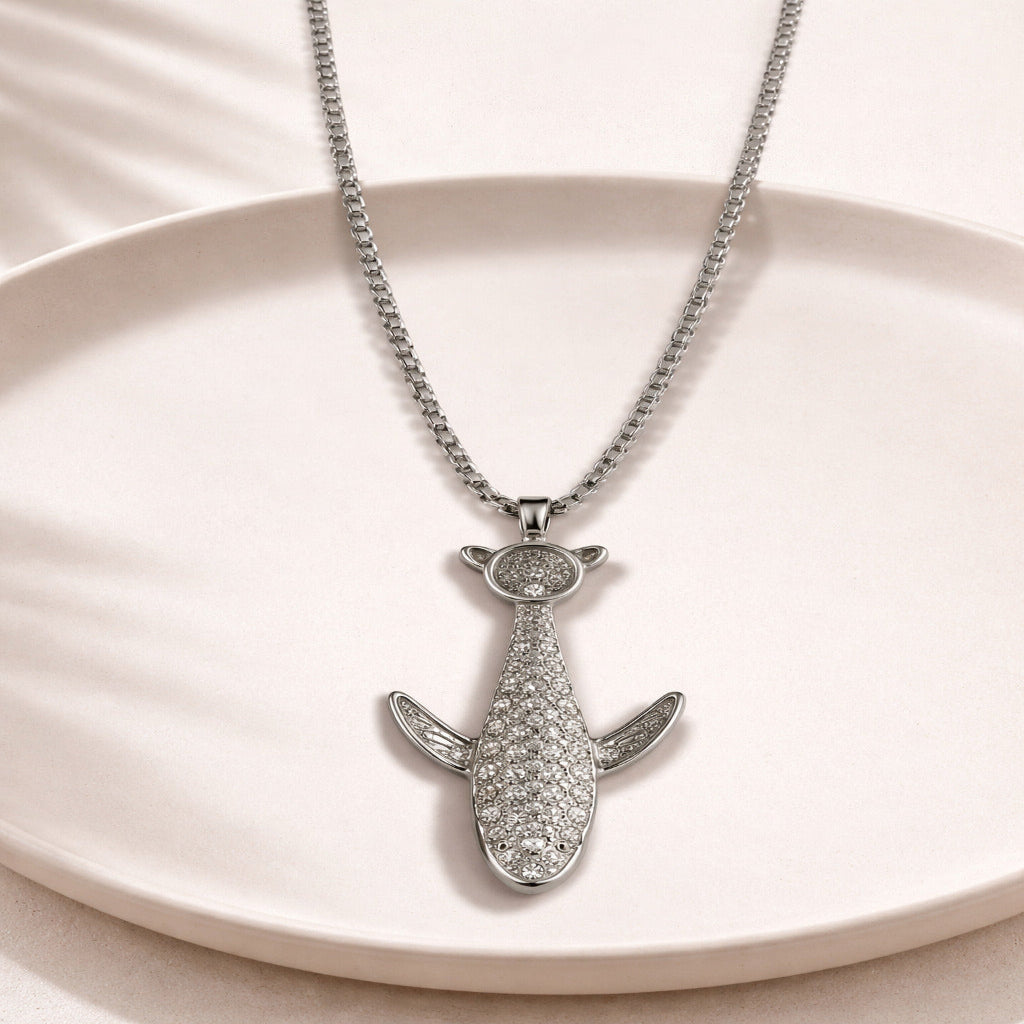 Silver shark-shaped pendant necklace on a beige plate
