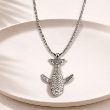 Silver shark-shaped pendant necklace on a beige plate