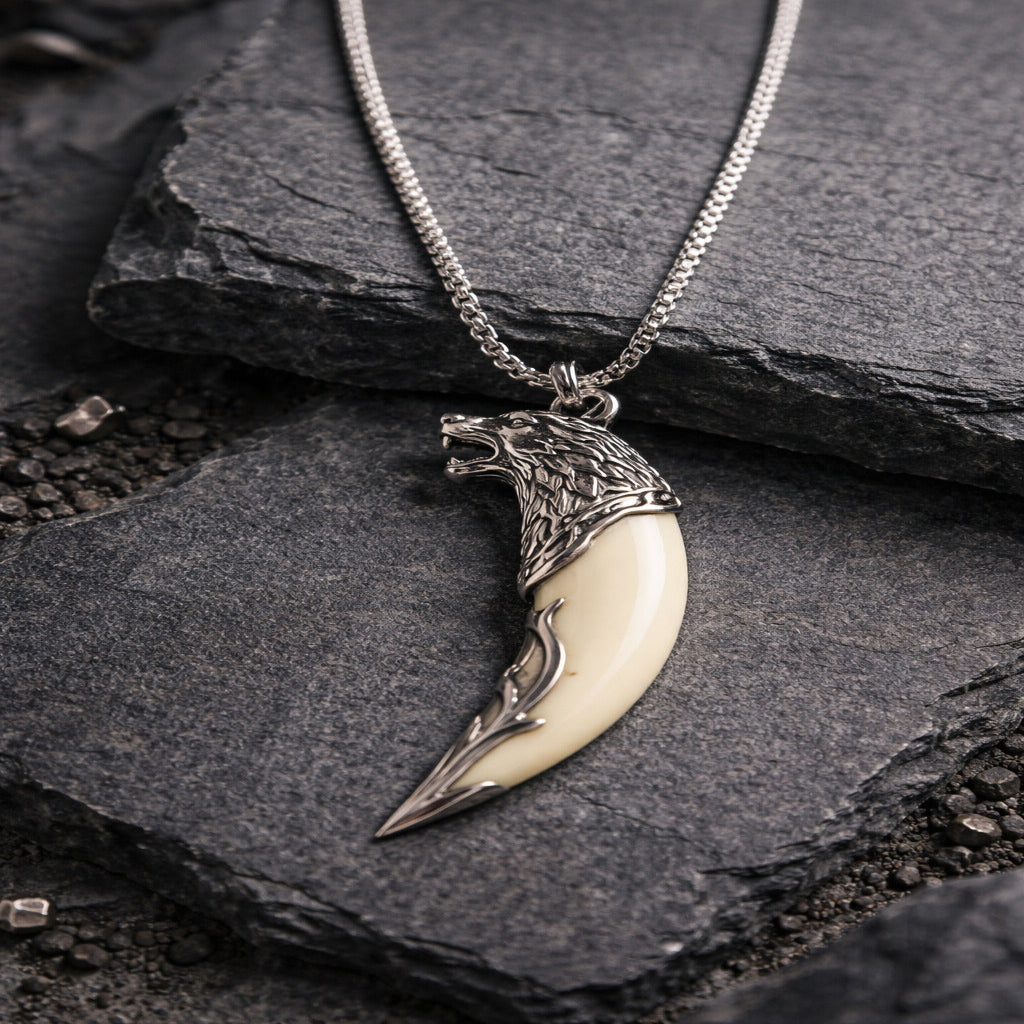 Silver and ivory pendant necklace on a dark stone surface