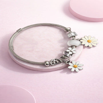Silver bracelet with floral charms on a pink background