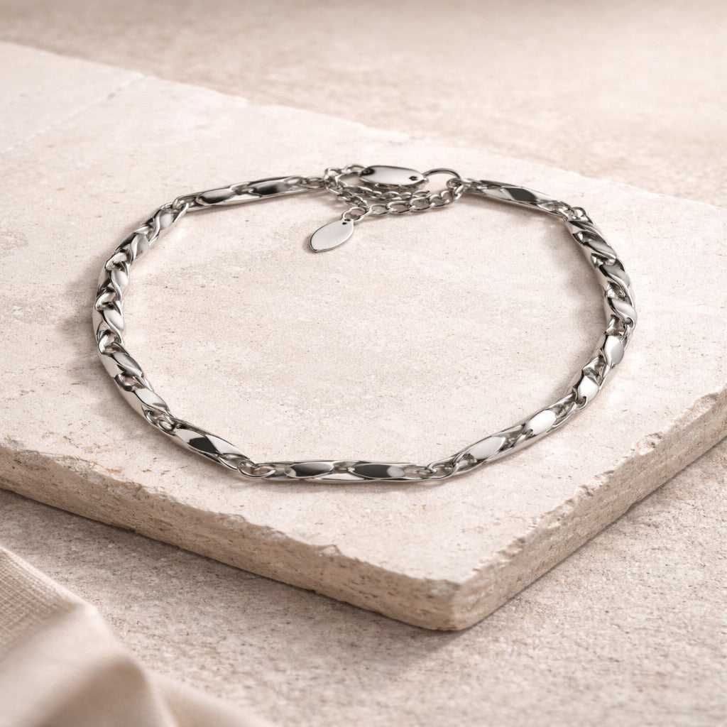 Silver chain bracelet on a beige stone surface