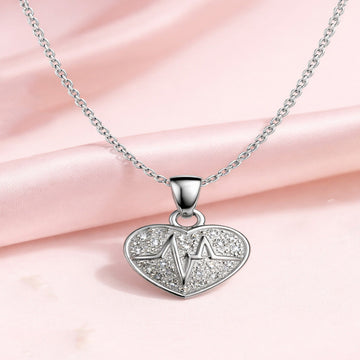 Silver heart-shaped pendant necklace with a star design on a pink fabric background