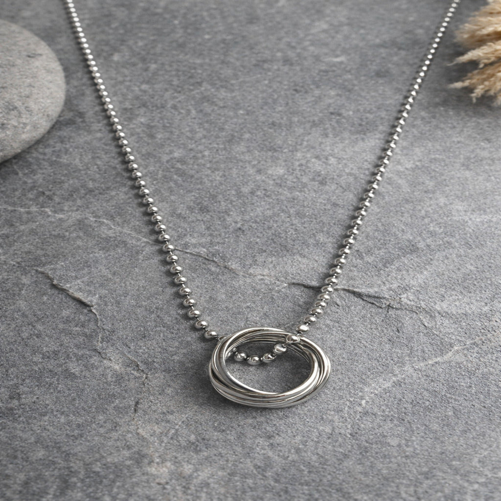 Silver necklace with a circular pendant on a gray surface