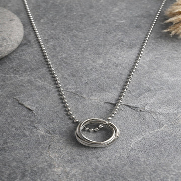 Silver necklace with a circular pendant on a gray surface