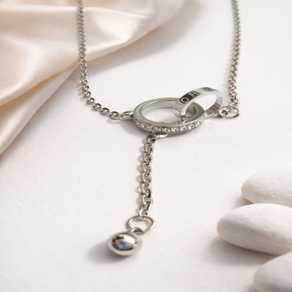 Silver necklace with rings and a pendant on a light fabric background