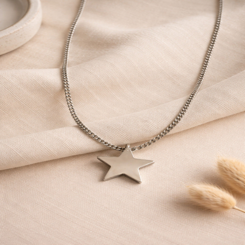 Silver star necklace on a beige fabric background