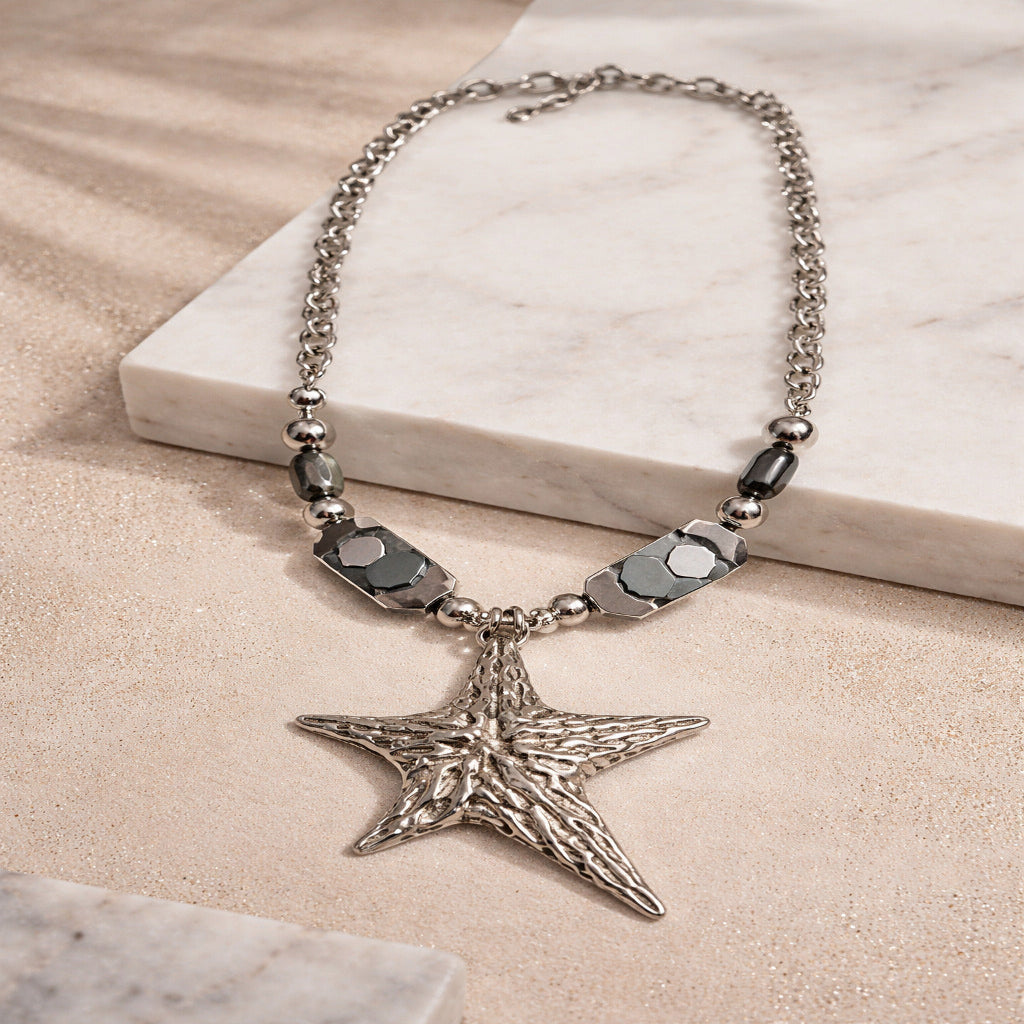 Silver star-shaped pendant necklace on a marble surface