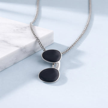 Necklace with black pendant on a light blue surface