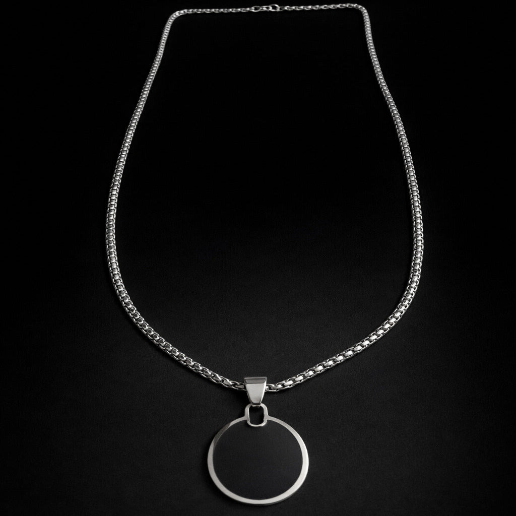 Silver necklace with a circular pendant on a black background