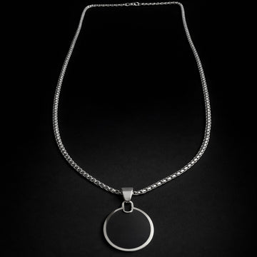 Silver necklace with a circular pendant on a black background