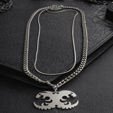 Silver chain necklace with a pendant on a dark textured surface