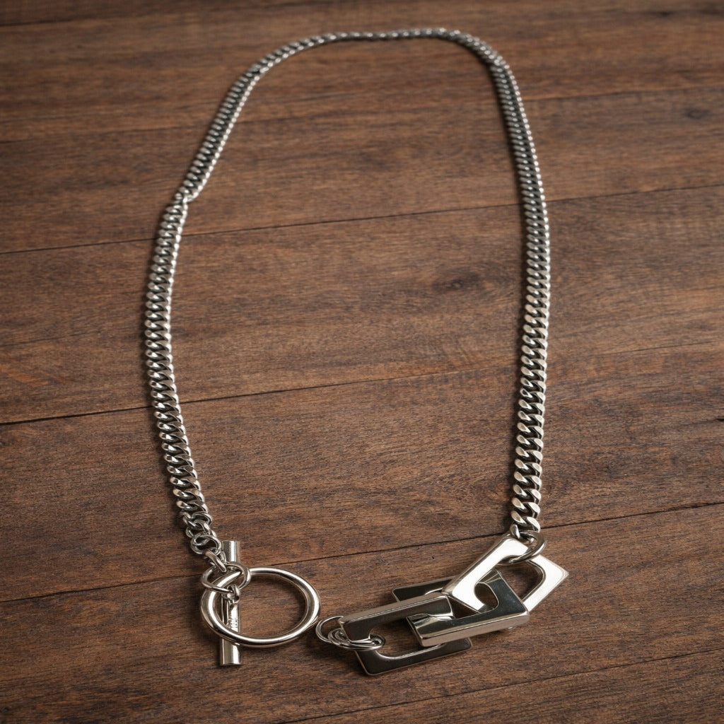 Silver chain necklace with clasp on a wooden surface