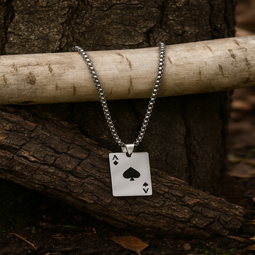 Silver necklace with an ace of spades pendant on a wooden branch.